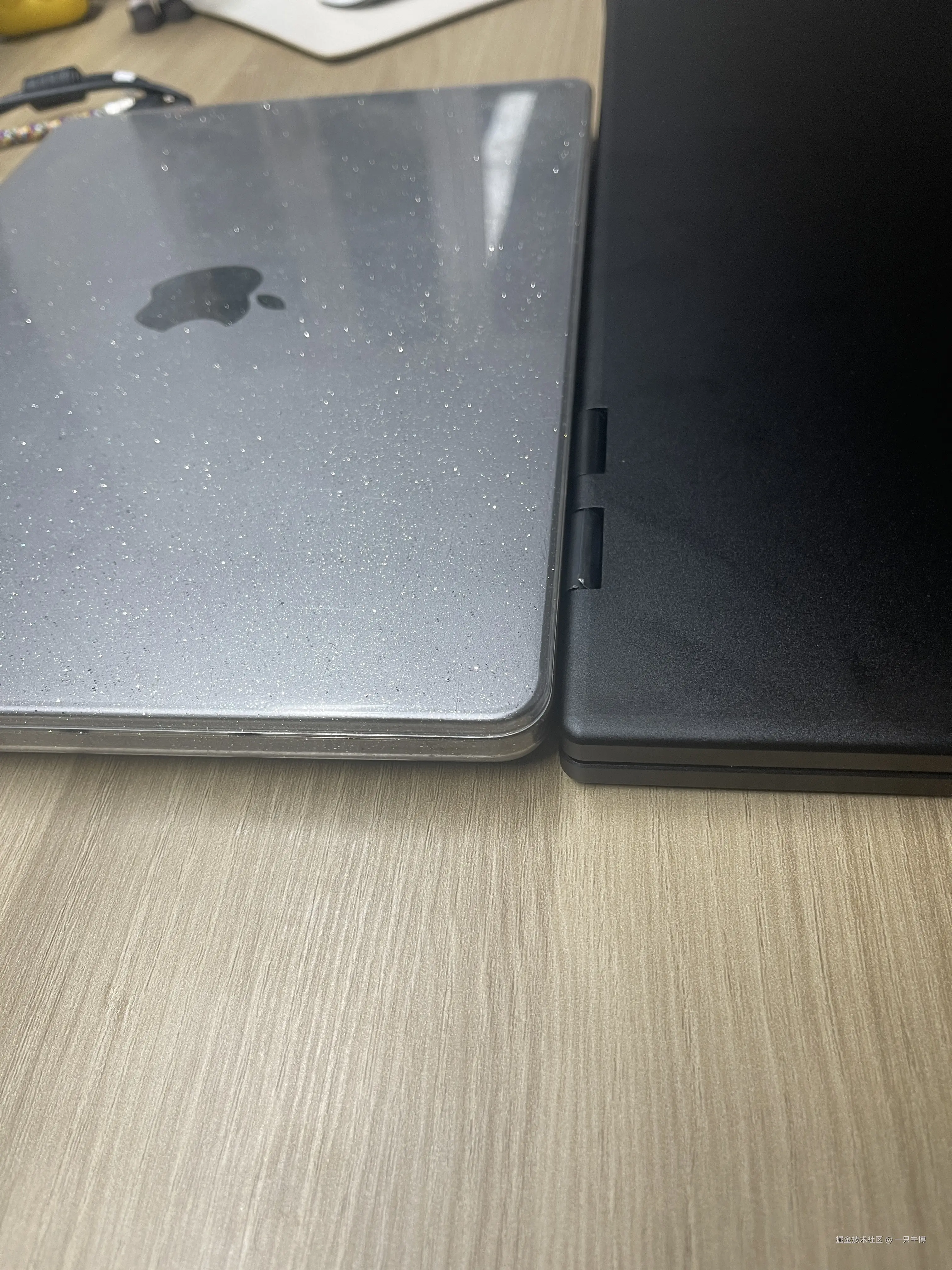 The monitor folded shut, stacked on top of a MacBook with a case to compare thickness