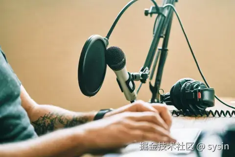Someone taking notes at a computer with a microphone on their desk